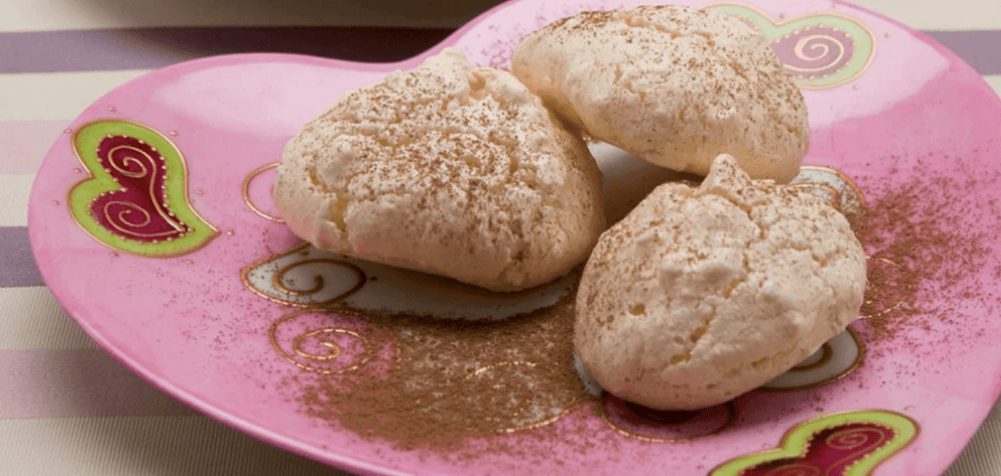 Delicate Sospirus cookies dusted with cocoa on a pink heart-shaped plate.