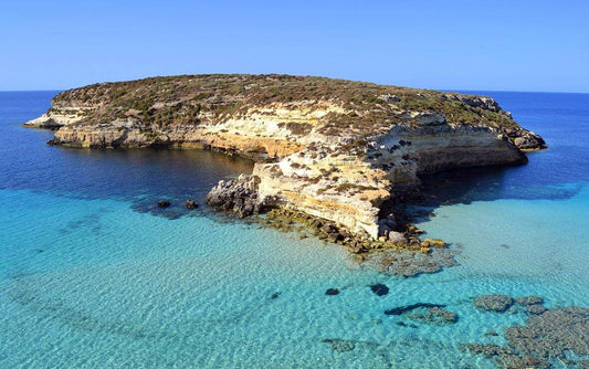 Lampedusa - spiaggia di sabbia bianca con mare cristallino turchese e falesie rocciose