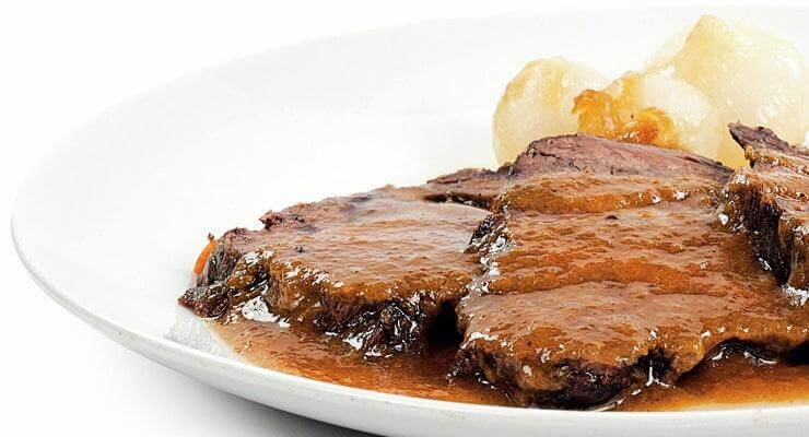 Bue alla Moda served with savory sauce and side dish on a white plate at Tastiness Food Shop.