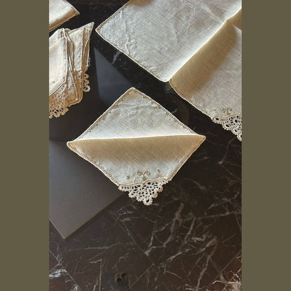 Set of vintage Burano lace napkins displayed on a dark marble table, showcasing intricate craftsmanship.