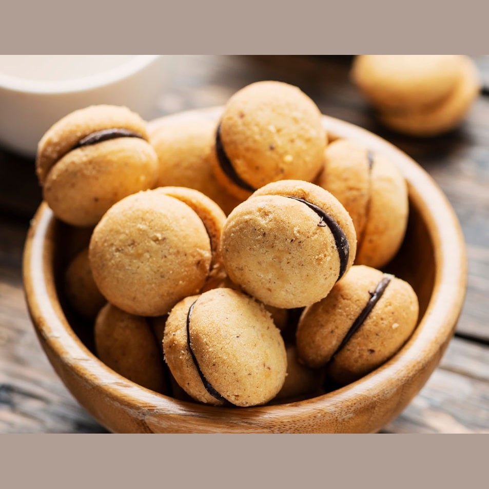 Baci di Dama in una ciotola di legno, dolciumi croccanti con ripieno di cioccolato, irresistibili e fatti a mano.
