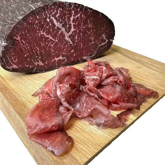 Trancio di bresaola Angus con fette disposte su un tagliere di legno