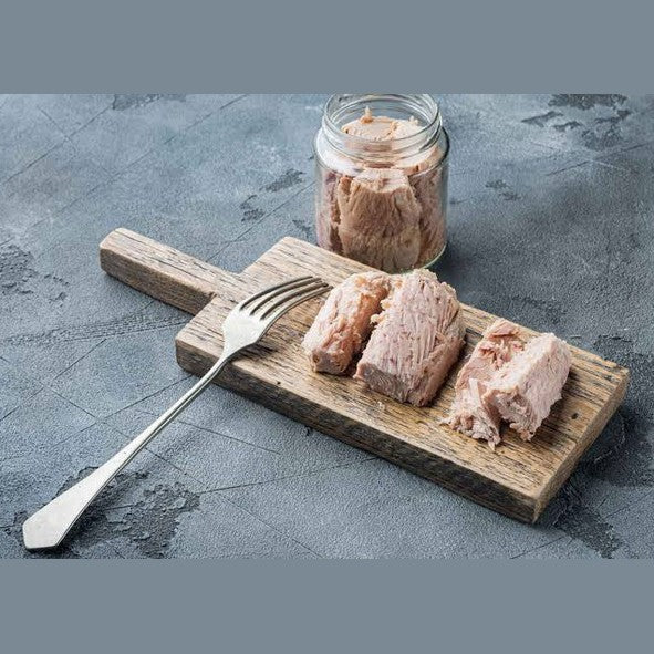 Filetti di Tonno Calabrese in olio d'oliva serviti su un tagliere di legno con forchetta