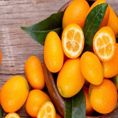 Fresh kumquats in a wooden bowl, showcasing whole and sliced fruit, perfect for desserts and cocktails.