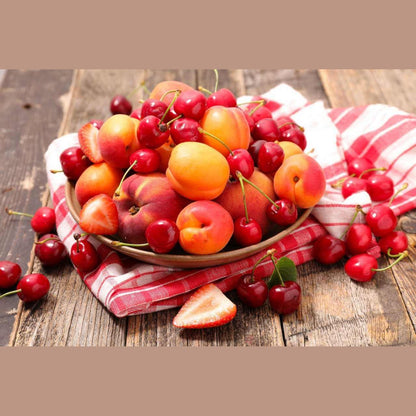 Mixed seasonal fruit bowl featuring cherries, apricots, and peaches on a rustic wooden table.