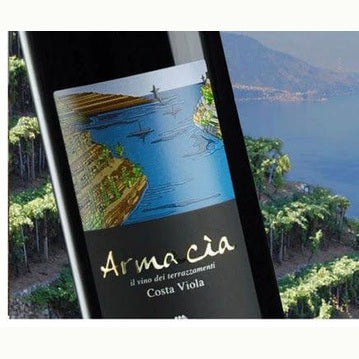 Armacia IGT Calabria Rosso wine bottle with scenic Costa Viola terraced vineyards in background.