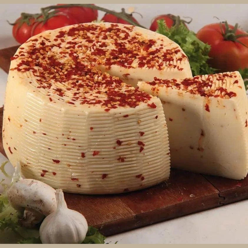 Formaggio di Pecora al Peperoncino - Sicilian cheese with chili, sliced and displayed on a wooden board.