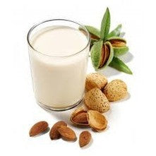 Pasta di Mandorla and almond milk in a glass with whole and cracked almonds.