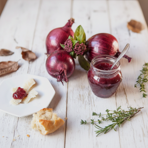 Paté Artigianale di Cipolla Rossa in un barattolo con tartine e cipolle rosse fresche sullo sfondo.